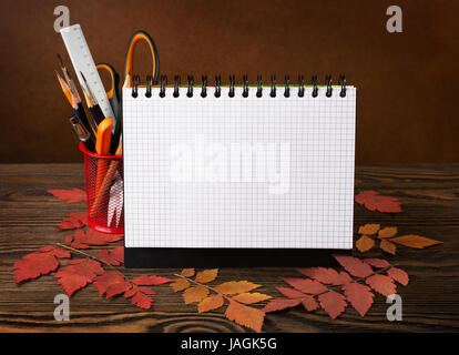 School equipment with pencils,  brushes, notebook  and autumn leaves on wooden table . Back to school concept. Stock Photo