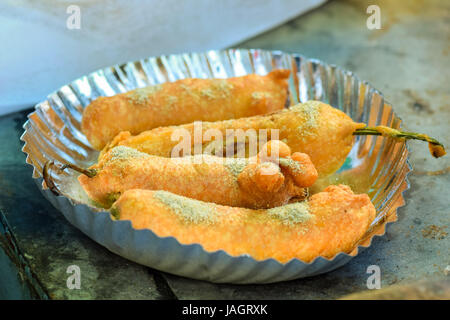 Green Mirchi Pakora or Hot Bhajiya or Green Chilli Cutlet served in a disposable plate with masala Stock Photo