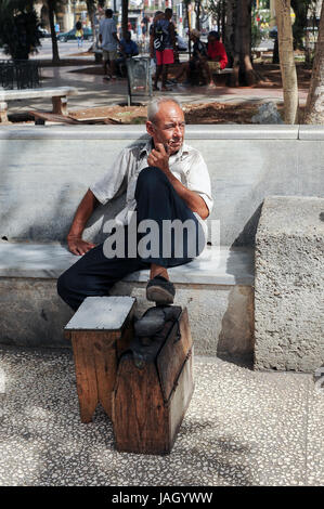 Shoeshiner smoking pipe waiting for clients in Old Havana, Cuba Stock Photo