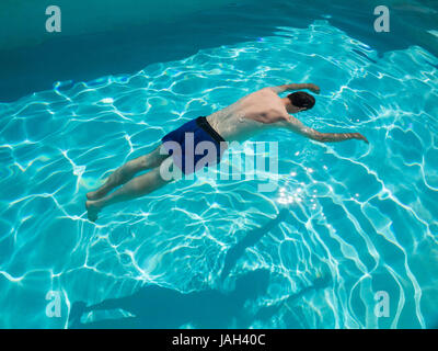 Motionless body of swimmer (drowned?), floating in swimming pool (concept photo, posed by model). Stock Photo