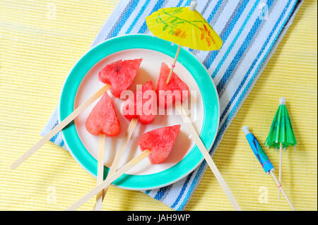 fruit pops of watermelon in heart shaped shoot in studio. watermelon heart as lollipop Stock Photo