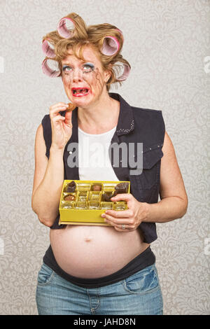 Depressed pregnant hick eating from box of chocolates Stock Photo