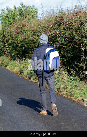 Young man carrying backpack walking away from camera Stock Photo