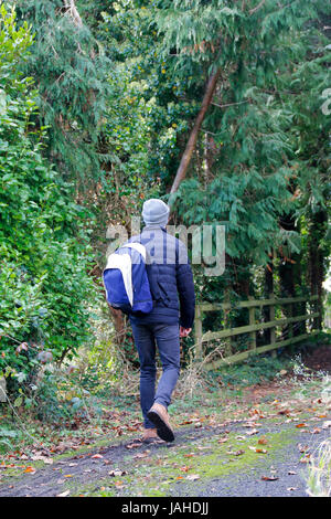 Young man carrying backpack walking away from camera Stock Photo