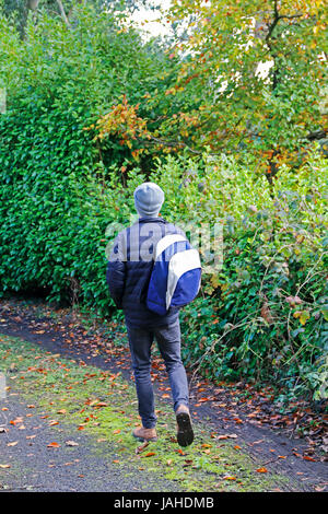 Young man carrying backpack walking away from camera Stock Photo