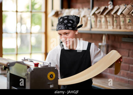 Woman cooks dough on machine for making pasta Stock Photo