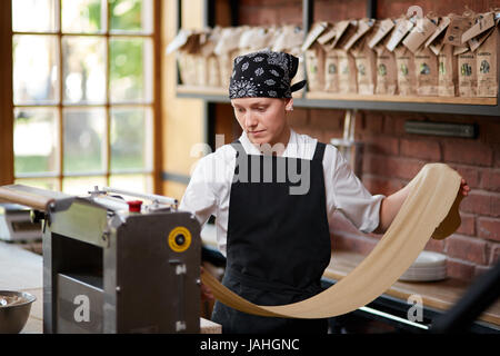 Woman cooks dough on machine for making pasta Stock Photo