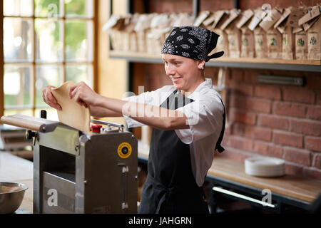 Woman cooks dough on machine for making pasta Stock Photo