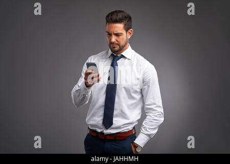 A handsome young man feeling upset while holding and looking at his smartphone Stock Photo