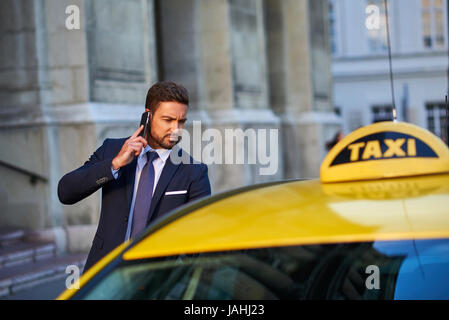 A handsome young businessman getting in to a taxi while talking on his phone Stock Photo