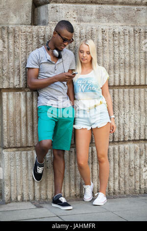 lachende junge freunde im sommer in der stadt mit mobiltelefon