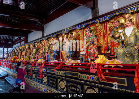 Worshiper praying in front of Brightly painted Taoist deities, Temple of Mystery, a Taoist complex founded in Song Dynasty, Suzhou, Jiangsu Province,  Stock Photo