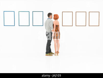 man and woman holding hands in front of empty frames displayed on white walls Stock Photo