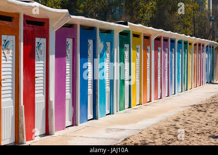 A row of beach huts with brightly coloured doors on sandy beach, Rimini, Italy Stock Photo
