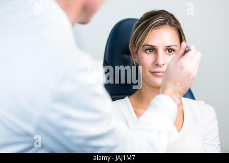 Optometry concept - pretty young woman having her eyes examined by an eye doctor/optometrist (color toned image; shallow DOF) Stock Photo