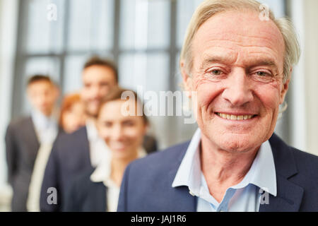 Senior man as the boss or chief executive smiling with his team Stock Photo