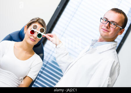 Optometry concept - pretty young woman having her eyes examined by an eye doctor/optometrist (color toned image; shallow DOF) Stock Photo