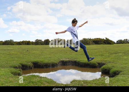 Young boys play jumping over puddles in the New Forest Stock Photo