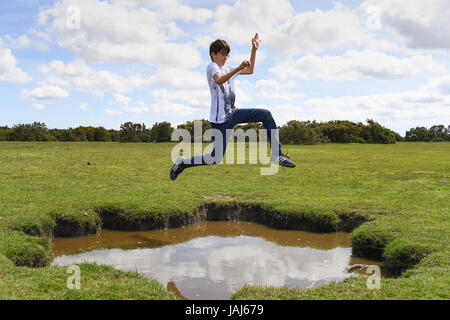 Young boys play jumping over puddles in the New Forest Stock Photo