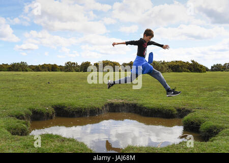 Young boys play jumping over puddles in the New Forest Stock Photo