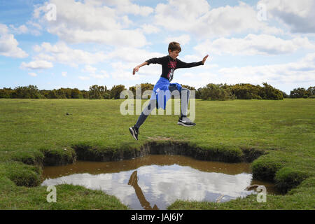 Young boys play jumping over puddles in the New Forest Stock Photo