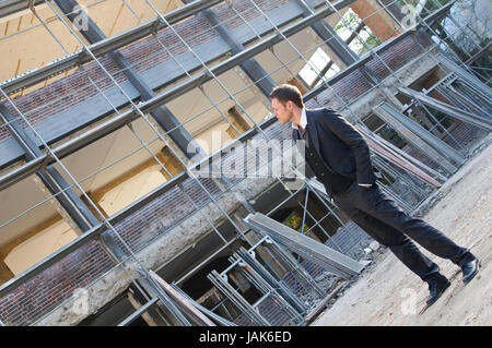 Junger Mann im dunklen Anzug auf einer Baustelle. Stock Photo