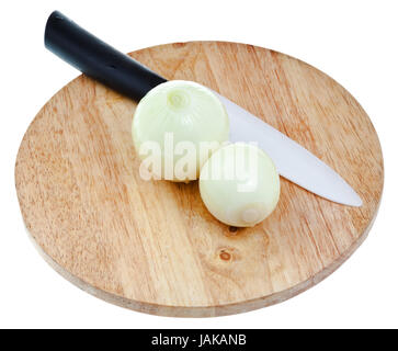 two peeled onions bulbs with ceramic knife on wooden cutting board isolated on white background Stock Photo