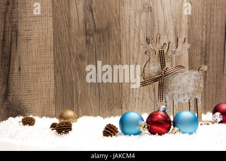 Weihnachten, Dekoration mit Holzhintergrund, Schnee, Elch, Weihnachtskugeln gold, blau und rot und Tannenzapfen Stock Photo