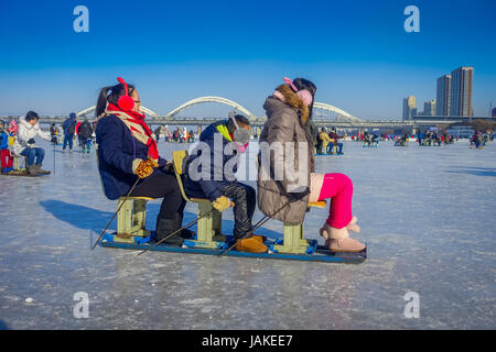 Harbin, China - February 9, 2017: Friends on a sled having fun on frozen river Songhua during winter time. Stock Photo