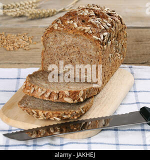 Frisches Vollkornbrot liegt auf einem Holzbrett neben einem Brotmesser Stock Photo