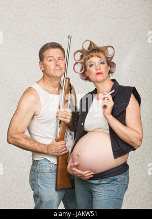 Negligent pregnant hillbilly couple with rifle and cigarettes Stock Photo