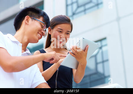 happy young asian or Chinese people using tablet outdoor Stock Photo