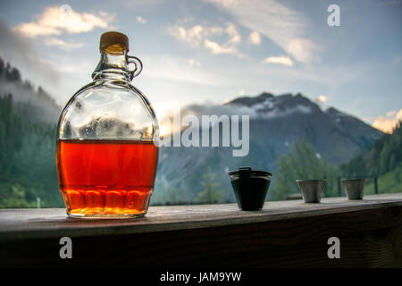 Drinking plum brandy after a long hiking tour in the mountains in Austria during sunset Stock Photo