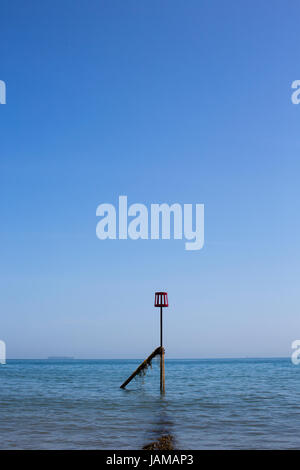 A red marker at the end of a groyne on the beach in Sandown, Isle of Wight, on a sunny summer day. Stock Photo