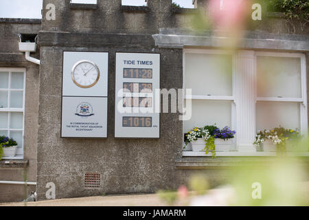 Tide times and a Rolex clock on a wall outside of the Royal Yacht Squadron, Cowes, Isle of Wight. Stock Photo