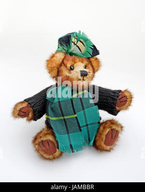 Cute cuddly Scottish teddy bear wearing woolly jumper, tartan scarf, and beret with tartan feather plume. Stock Photo