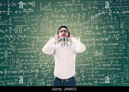 Young man solving mathematical equation on green blackboard Stock Photo