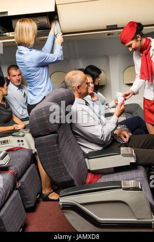 Flight attendant check passenger tickets in plane cabin Stock Photo