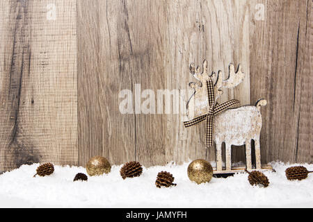 Weihnachten, Dekoration mit Holzhintergrund, Schnee, Elch, Weihnachtskugeln gold und Tannenzapfen Stock Photo