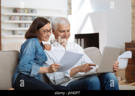 couple using their laptop to pay their bills at home in the living room Stock Photo