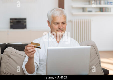 mature man using his laptop and holding his credit card Stock Photo