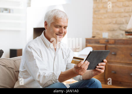 mature man using his laptop and holding his credit card Stock Photo