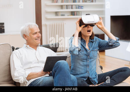 Mature couple using digital tablet and virtual reality headset in living room Stock Photo