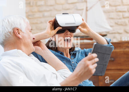 Mature couple using digital tablet and virtual reality headset in living room Stock Photo