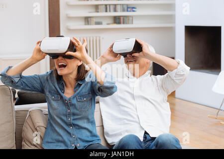 Mature couple using virtual reality headset in living room Stock Photo