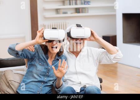 Mature couple using virtual reality headset in living room Stock Photo