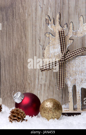 Weihnachten, Dekoration mit Holzhintergrund, Schnee, Elch, Weihnachtskugeln gold und rot und Tannenzapfen Stock Photo