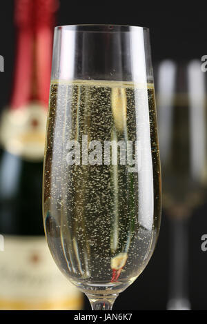 Champagner im Glas mit einer Flasche und weiteren Gläsern im Hintergrund Stock Photo