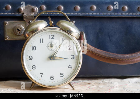 Last minute travel concept with old retro suitcase and alarm clock Stock Photo