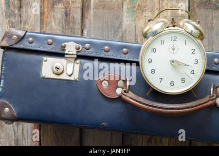 Last minute travel concept with old retro suitcase and alarm clock Stock Photo